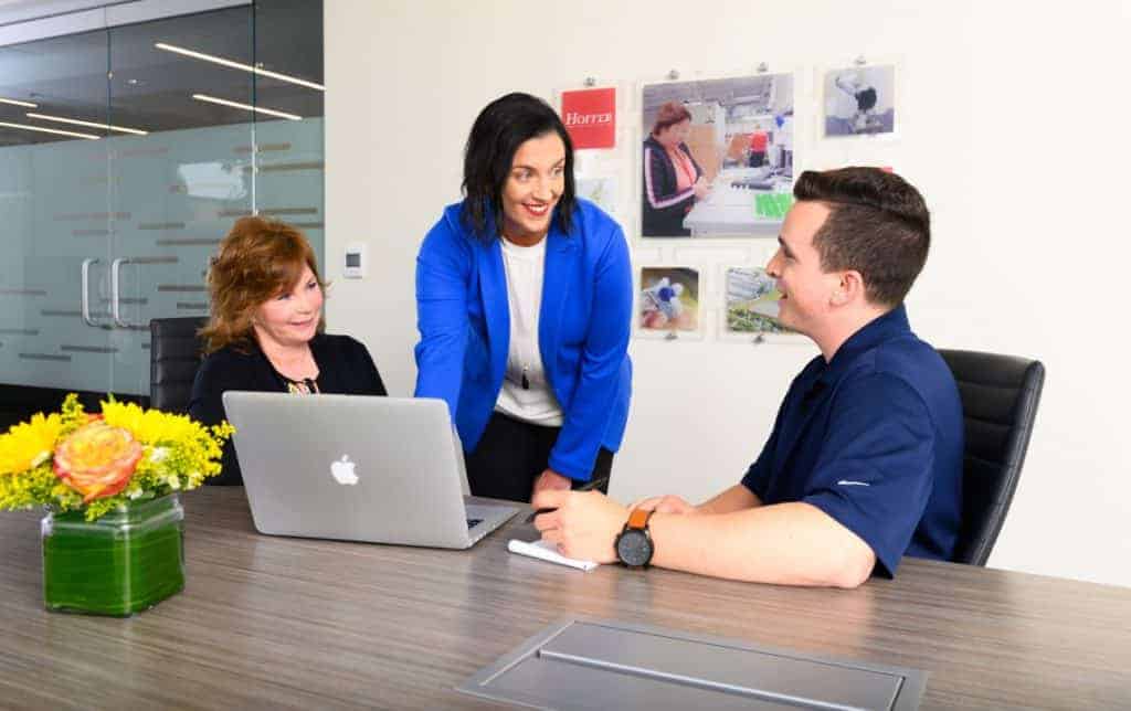 3 people at conference table with laptop