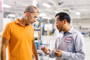 two men on factory floor looking at a plastic part