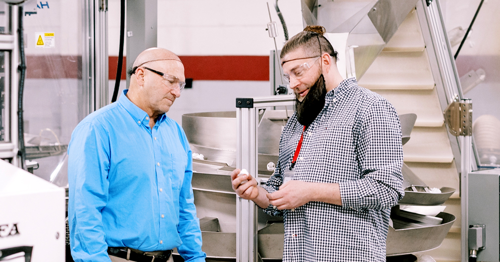 two hoffer plastics employees looking at plastic part