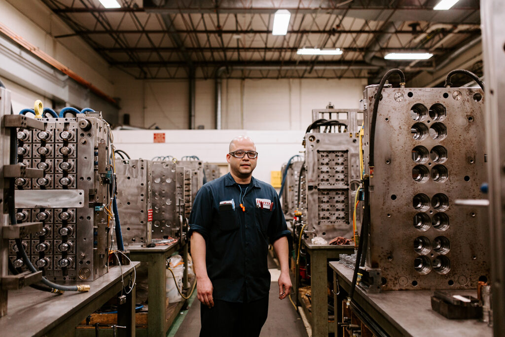 hoffer plastics tool room employee standing in front of large injection mold